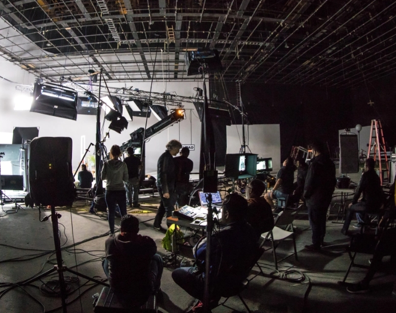Photo of a small film set with crew, lighting rigs and set dressing.