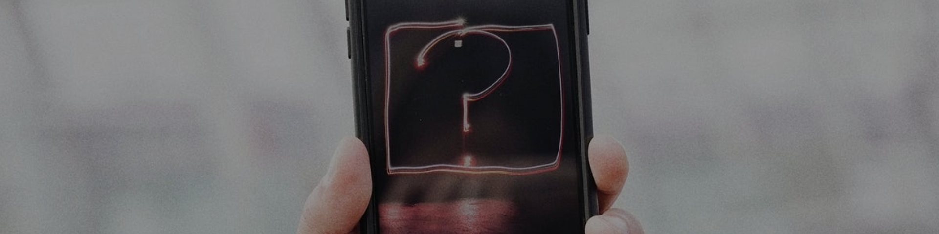 Photo of hand holding phone with question mark on the screen